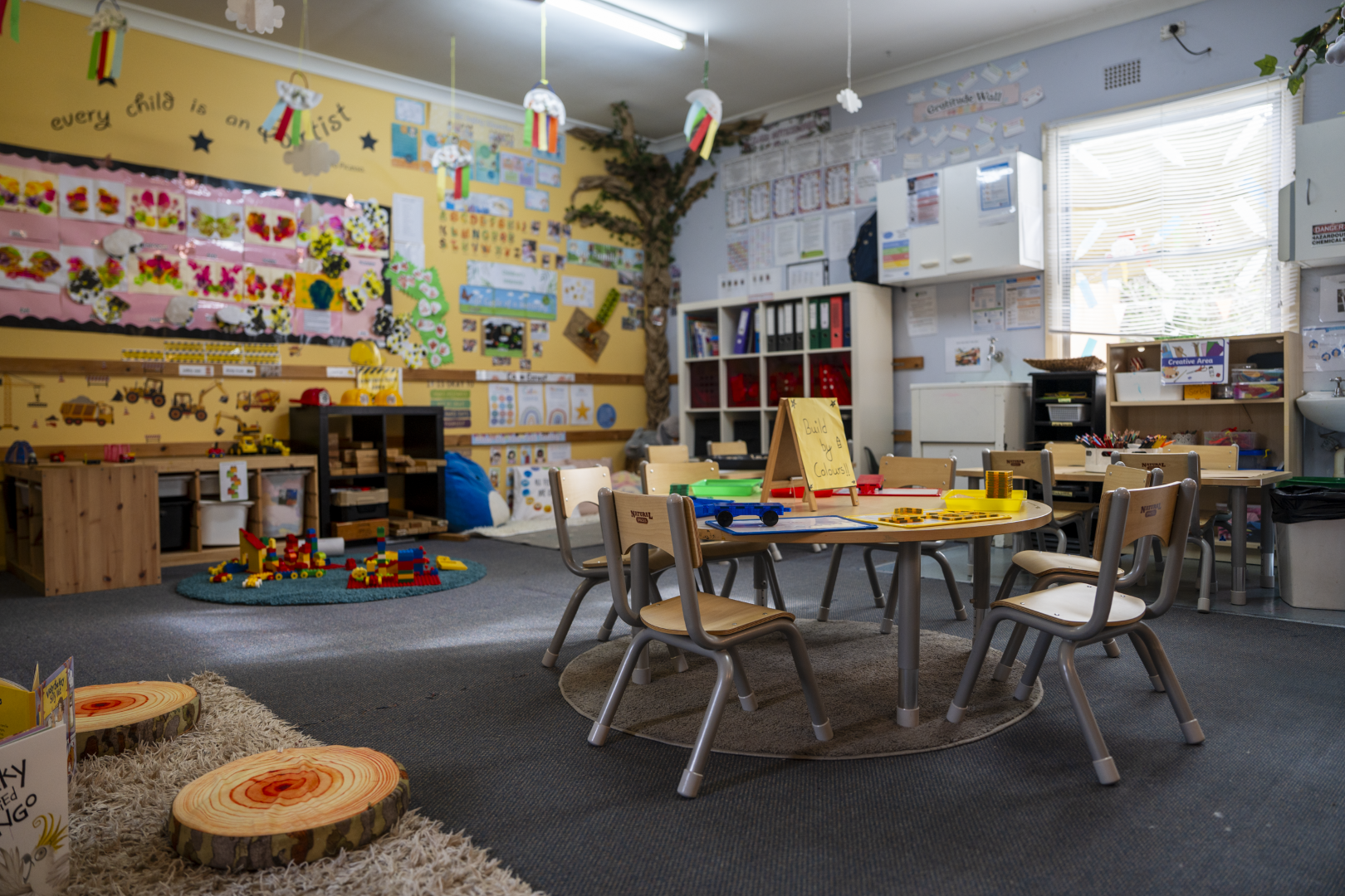 childcare classroom with small tables, chairs and colourful displays on the walls